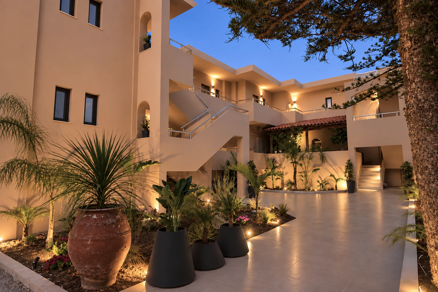 Eos Mare courtyard at dusk, with warm lighting, plants and balconies